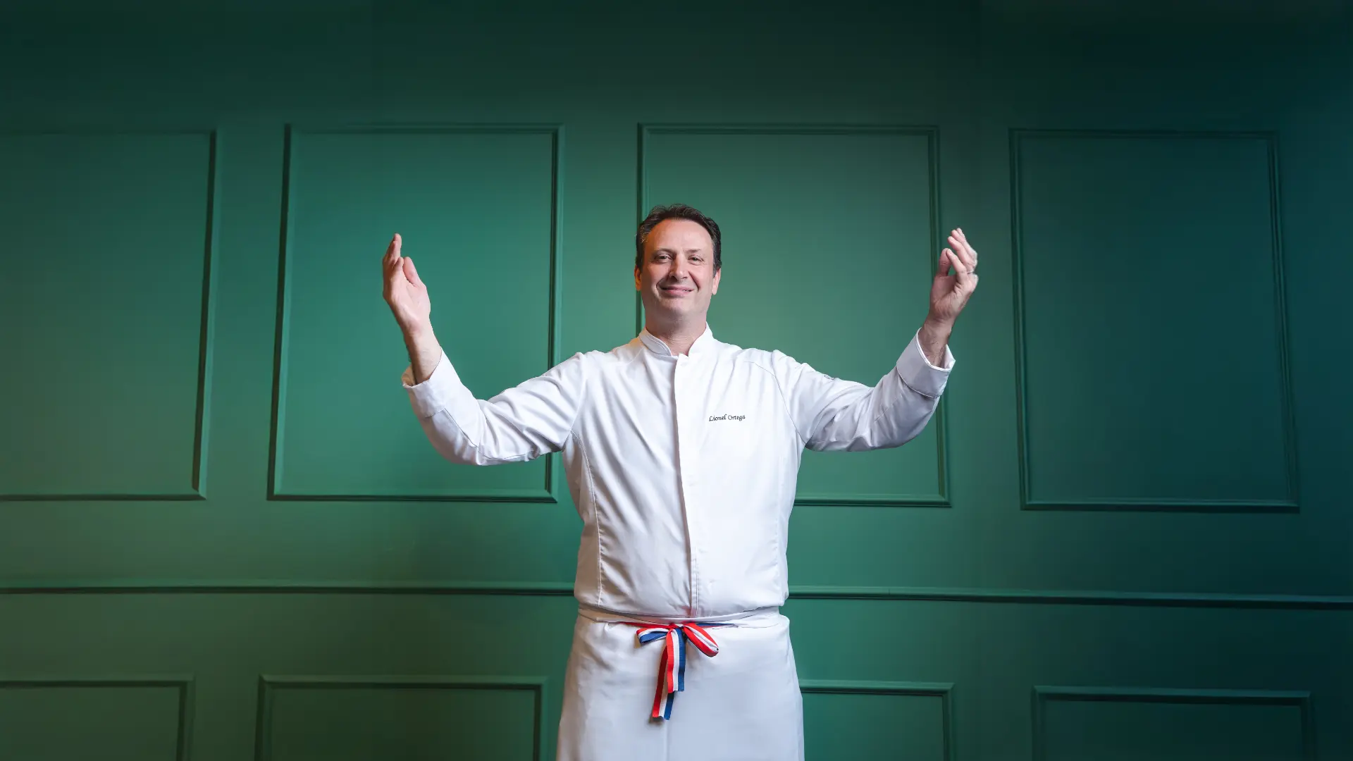 Chef Lionel Ortega de braços abertos em ambiente elegante